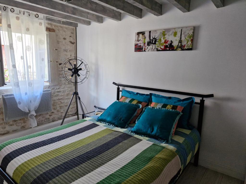 a bedroom with a bed with blue and green pillows at Chambre d'hote in Saint-Dizant-du-Gua