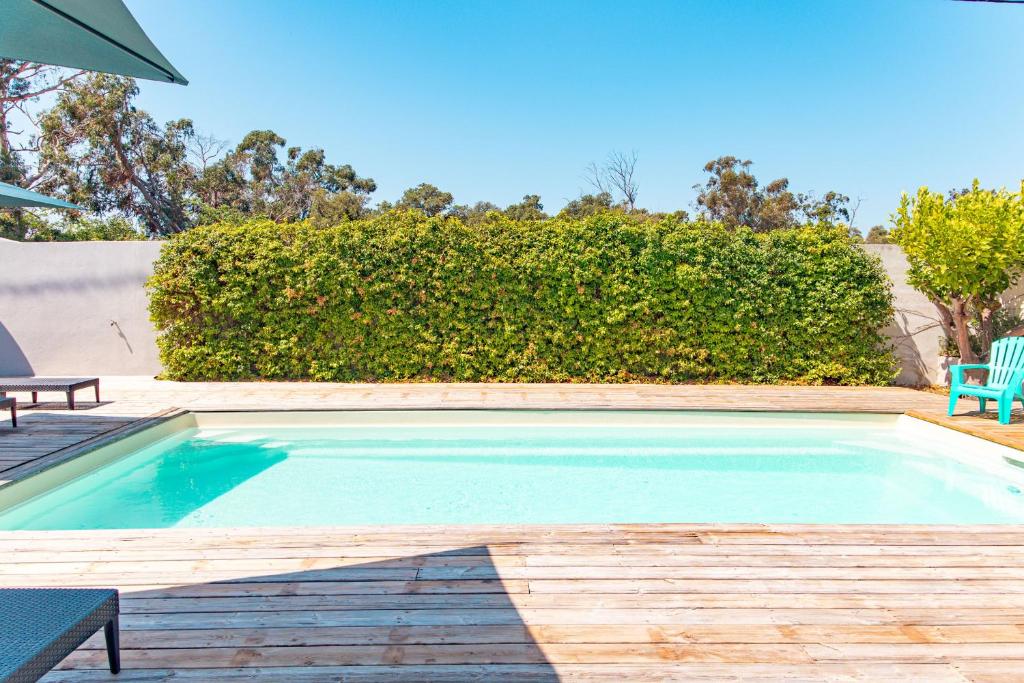 a swimming pool with a wooden deck and a blue chair at Villa Lisa Porto-Vecchio in Porto-Vecchio