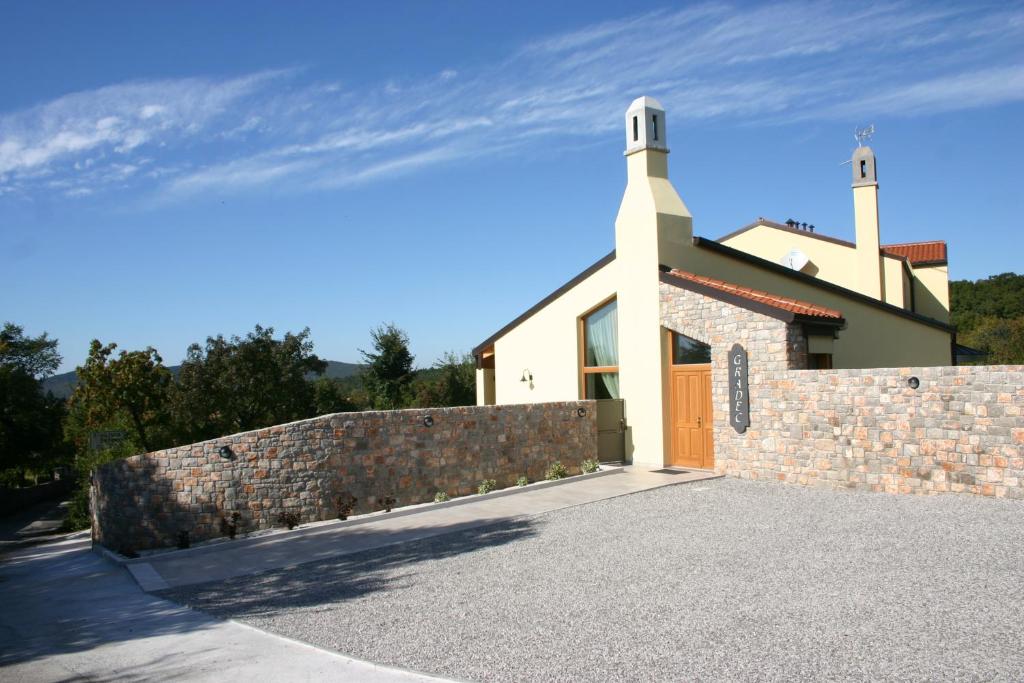 a church with a stone retaining wall and a fence at Agriturismo Gradec in Aurisina