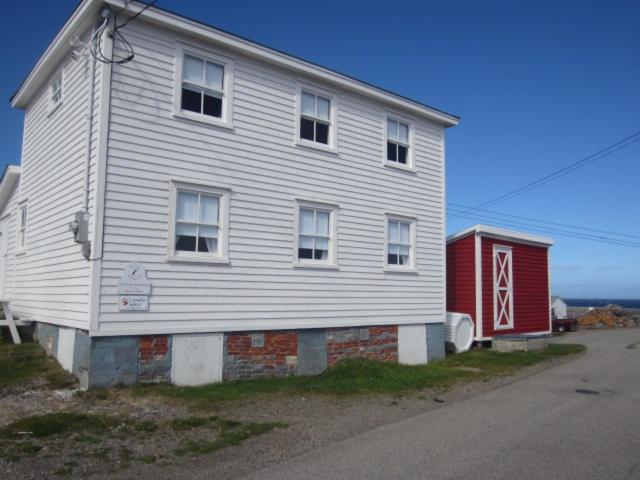 a white house with a red shed next to a street at The Old Salt Box Co. - Mary's Place in Fogo