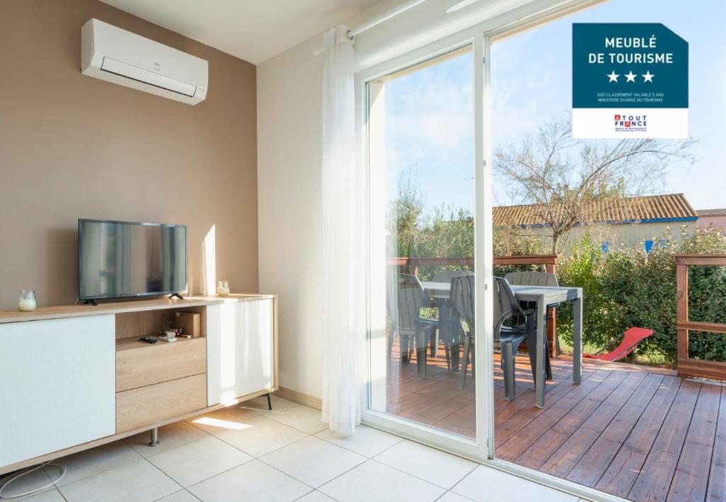 - un salon avec une porte coulissante en verre et une table à manger dans l'établissement La Dune N 25 - Villa 3P7, à Sérignan