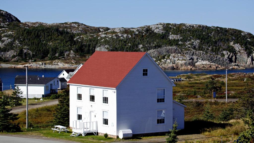ein weißes Haus mit rotem Dach vor einem Berg in der Unterkunft The Old Salt Box Co. - Evelyn's Place in Herring Neck
