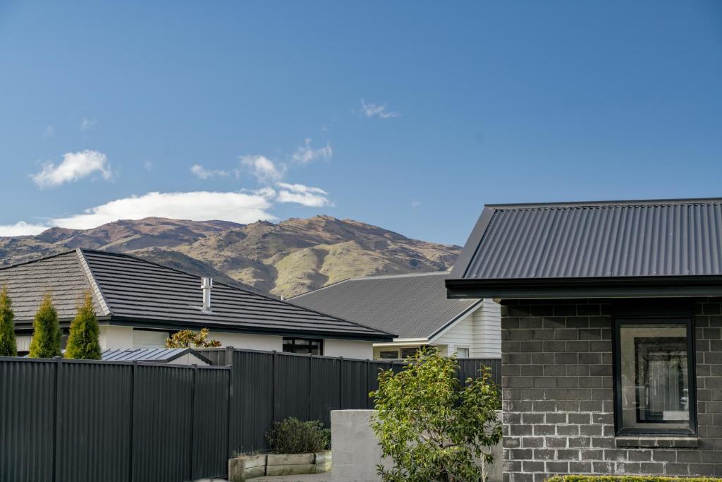 a house with a fence and mountains in the background at Sunrise Hideaway - Cromwell Holiday Home in Cromwell
