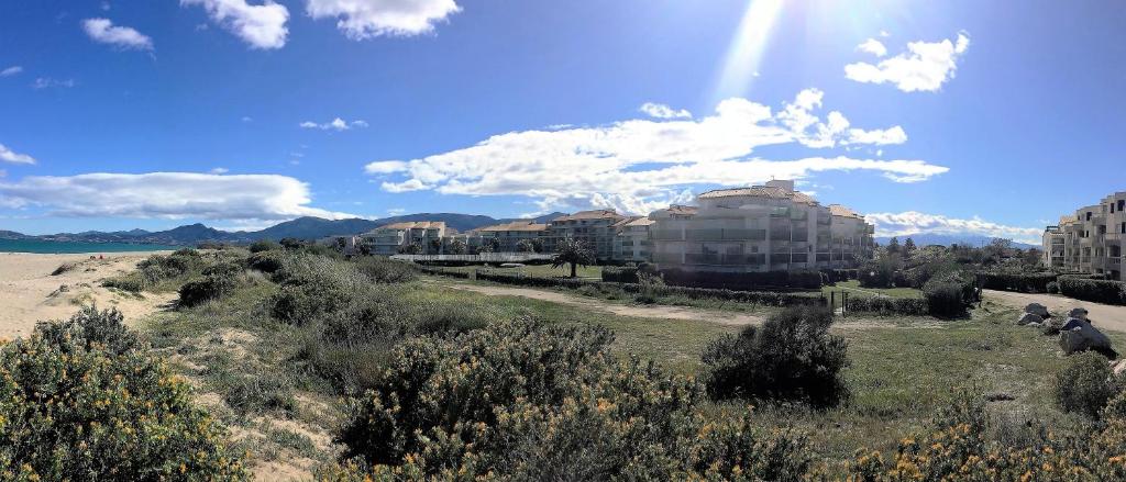 een uitzicht op een strand met gebouwen en de zon bij Résidence Les Goélettes in Saint Cyprien Plage