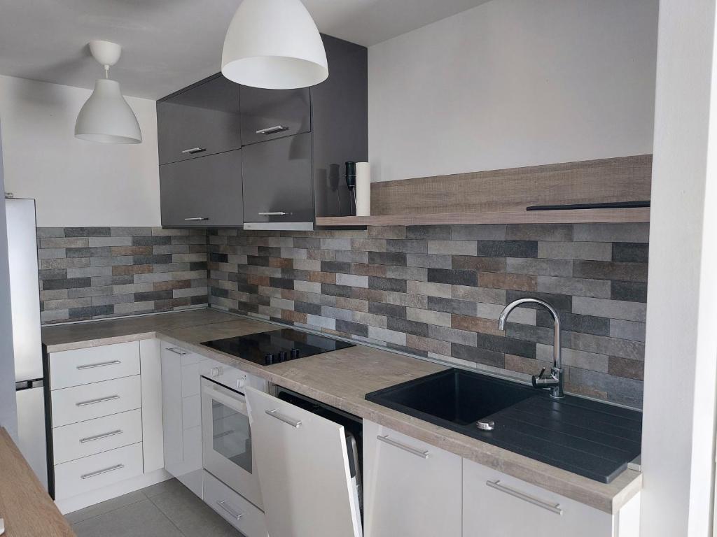 Una cocina con gabinetes blancos y un fregadero. en Dedinje Top, en Belgrado