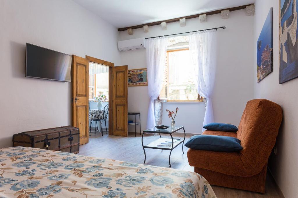 um quarto com uma cama, uma cadeira e uma televisão em Apartments Rudjer em Dubrovnik