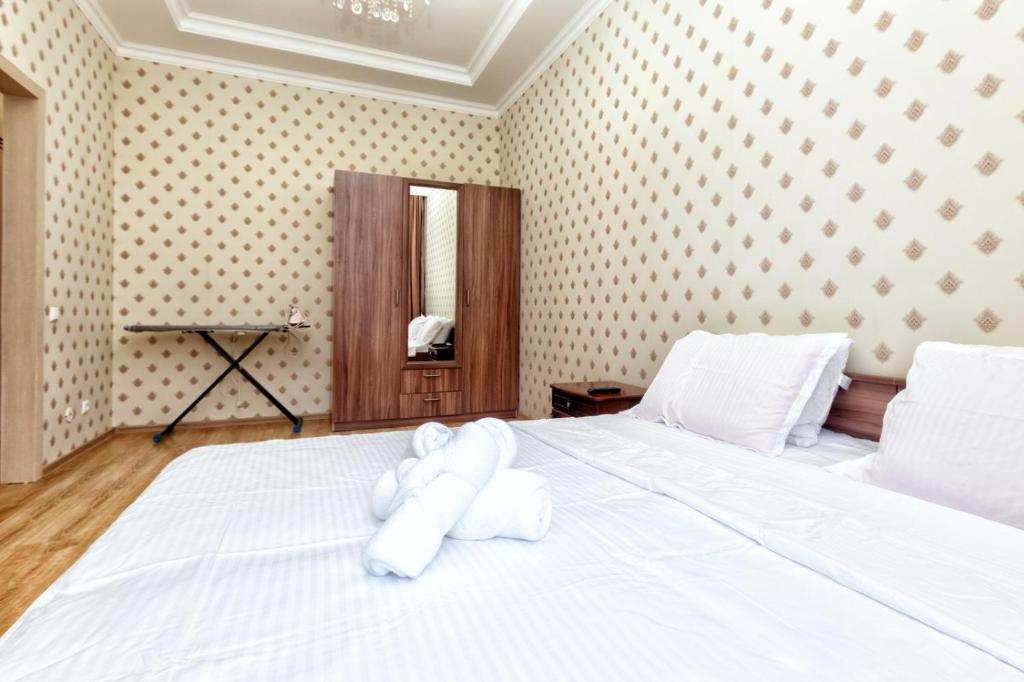 a white bed with a stuffed animal on it at Уютные вместительные апартаменты на Экспо in Zhezdi
