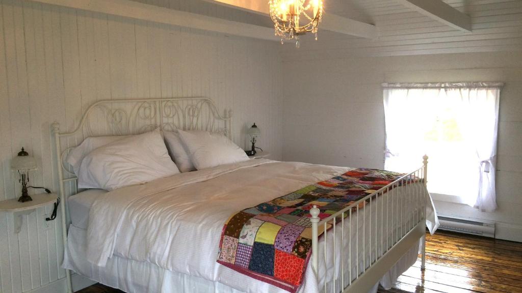 a white bed in a bedroom with a chandelier at The Old Salt Box Co. - Aunt Christi's in Greenspond