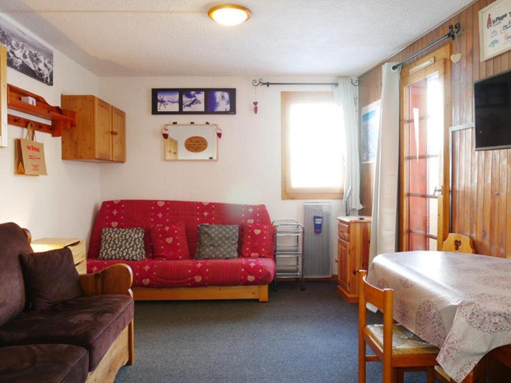 un salon avec un canapé rouge et une table dans l'établissement Studio rénové Montchavin proche commerces, pistes, avec balcon - FR-1-329-64, à La Plagne Tarentaise