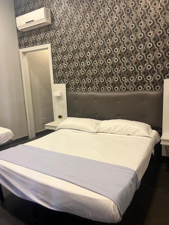 Un dormitorio con dos camas y una pared. en International Hotels, en Nápoles