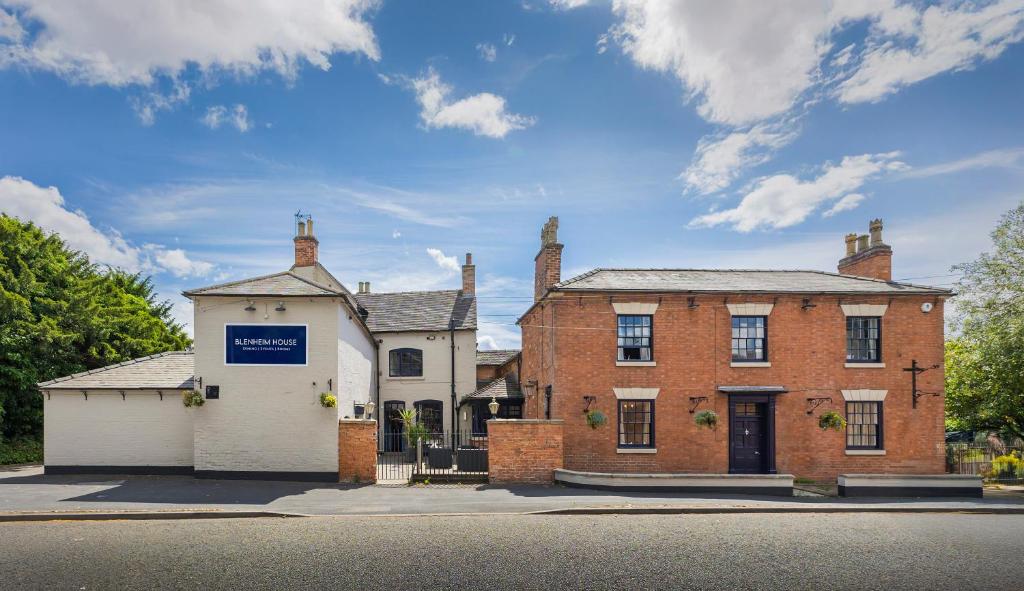 an old brick house with a blue sign on it at OYO Blenheim House in Etwall
