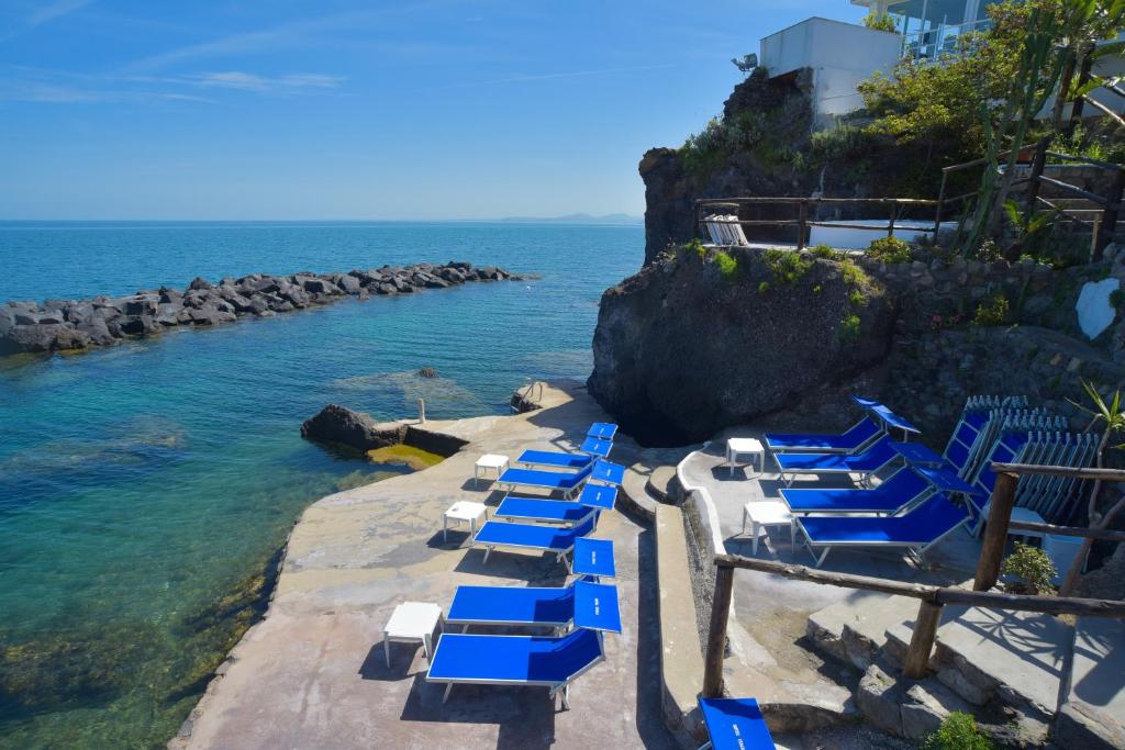 un grupo de sillones azules y blancos en el agua en Albergo Italia - Beach Hotel, en Isquia