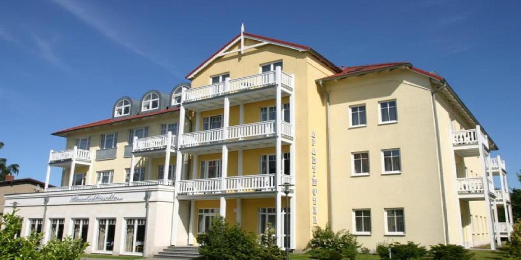 キュールングスボルンにあるStrandschlösschenの白いバルコニー付きの大きな黄色の建物