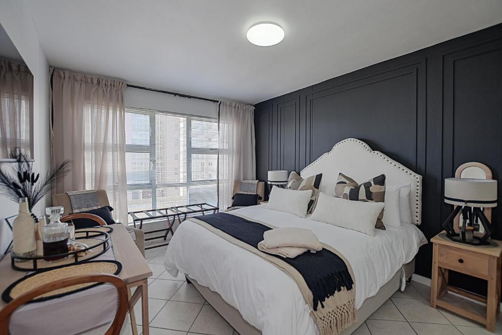 a bedroom with a large bed and a large window at Seehuys Beachfront Studio Sea & Mountain Views in Bloubergstrand