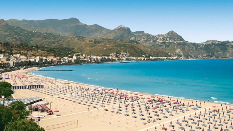 a beach with a bunch of umbrellas and the ocean at La Via del Mare in Giardini Naxos