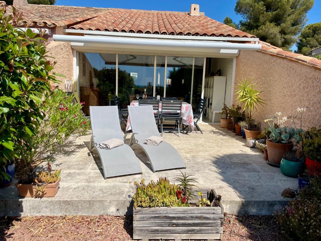 un patio avec deux chaises blanches et une table dans l'établissement Provenzalisches Haus Les Lauriers Roses - Garten mit Meerblick und Gemeinschaftspool by Riviera HomeLife, à Agay