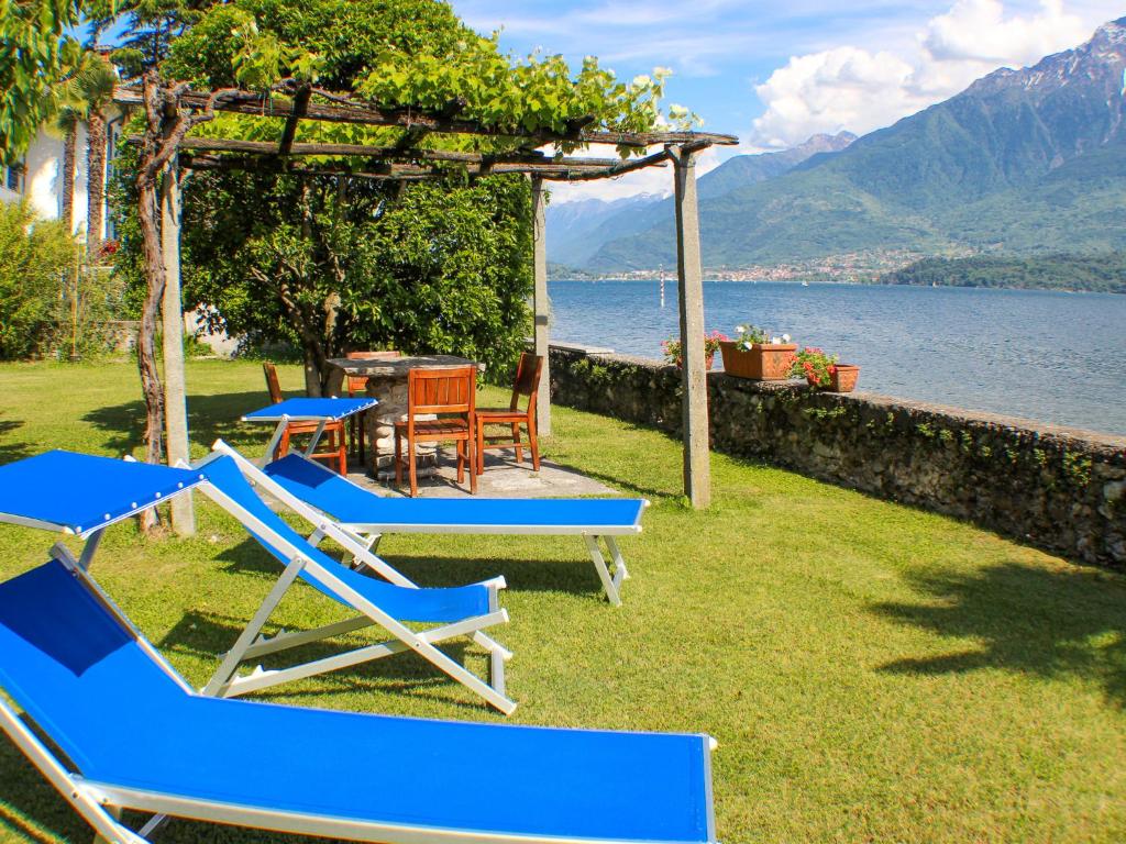 a group of blue lounge chairs and a pergola and water at Vento Blu in Domaso