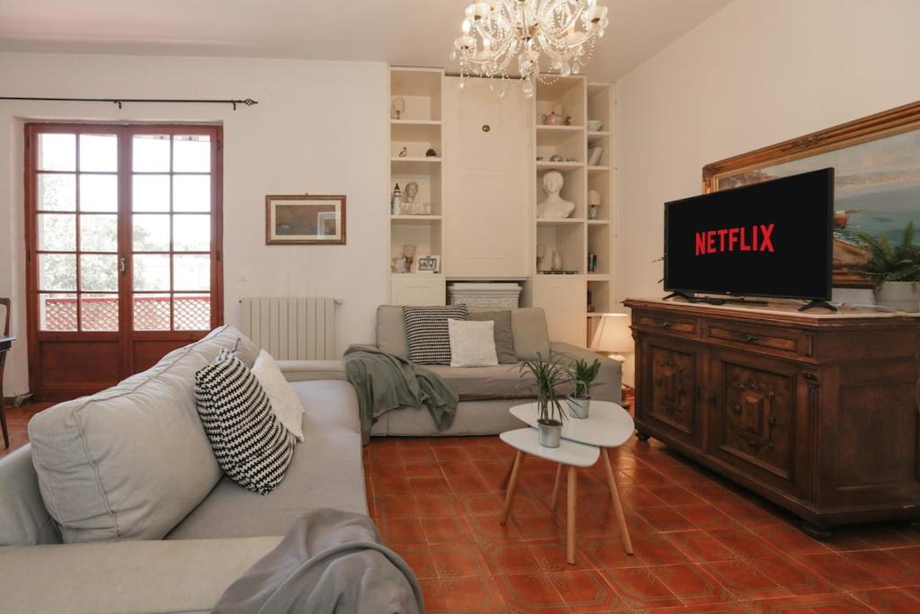 Una sala de estar con un sofá y un televisor. en FORTE DEI MARMI - 500m to the sea, en Marina di Massa