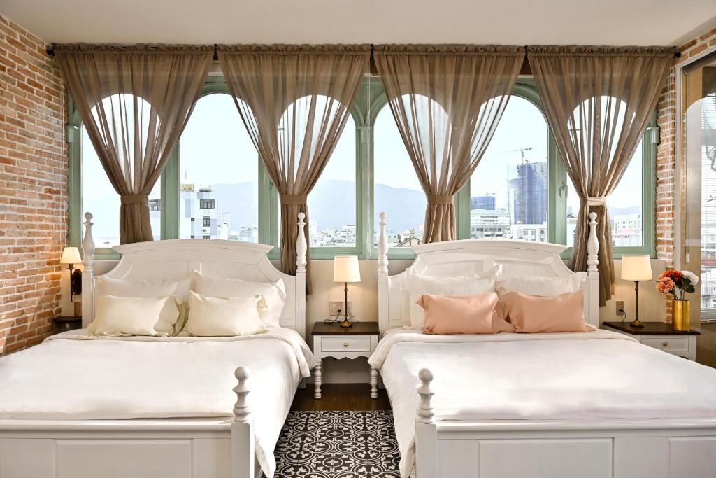 two white beds in a room with windows at The Luna Boutique Hotel in Quy Nhon