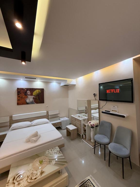 a room with a tv and two beds and chairs at Jacuzzi Escape in Tirana