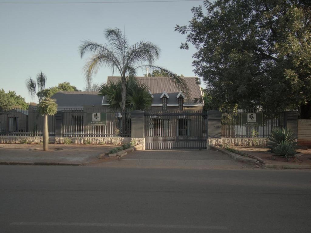 a house with a fence and a palm tree at Insolam Accommodation in Mokopane