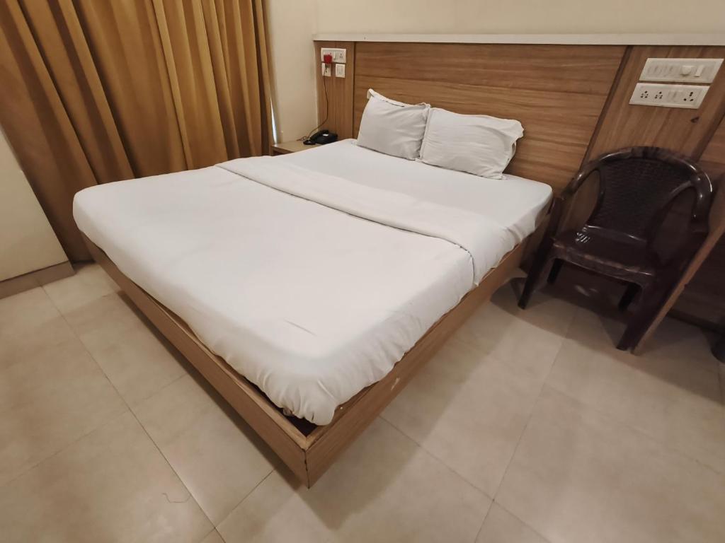 a bed in a small room with a chair at Paayal Lodging in Navi Mumbai