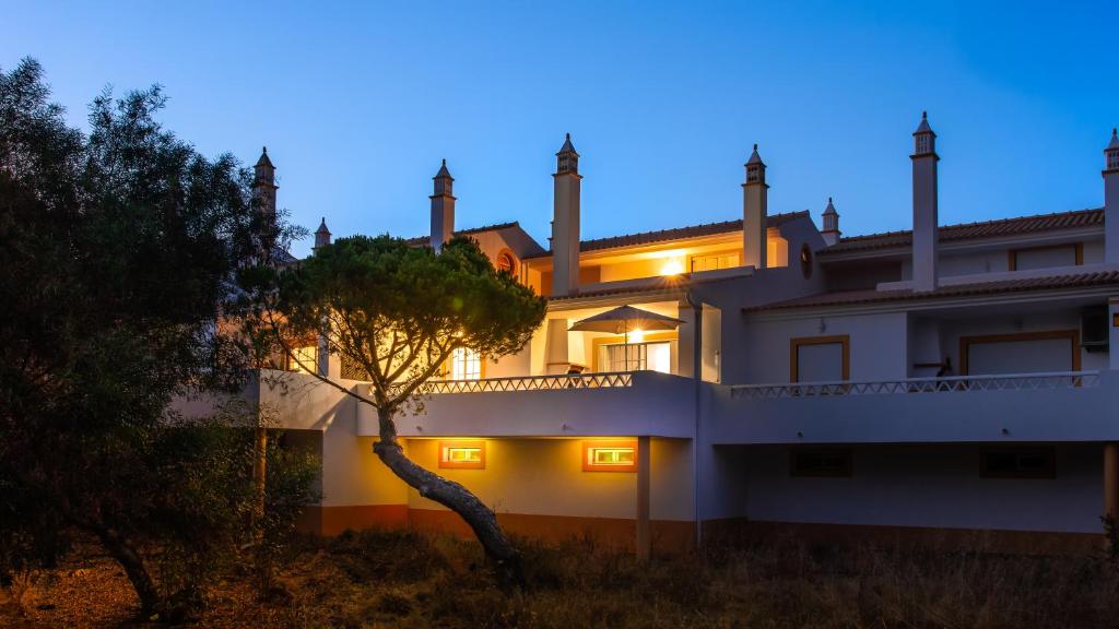 une grande maison blanche avec un arbre devant dans l'établissement Pine Cliffs by Check-in Portugal, à Albufeira