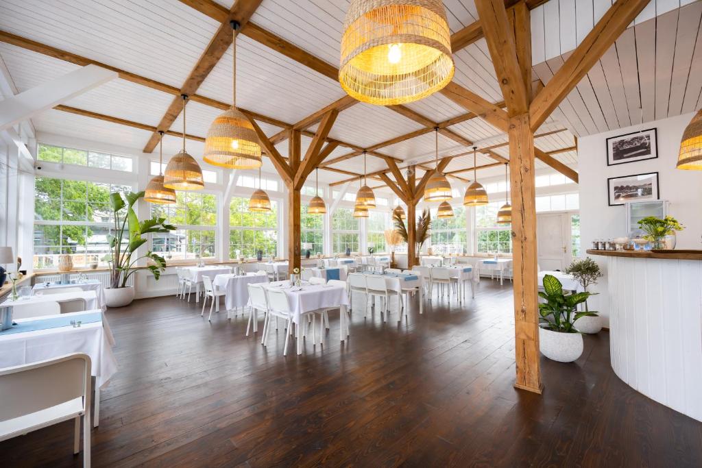 a dining room with white tables and white chairs at Enklawa - Floryn Mielno in Mielno