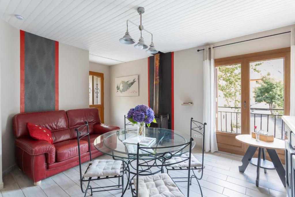 un salon avec un canapé rouge et une table en verre dans l'établissement Gîte Le Boisset, à Gincla