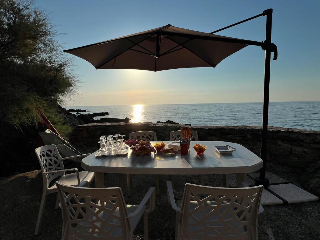 a white table with an umbrella and the ocean at U Magazinu in Pino