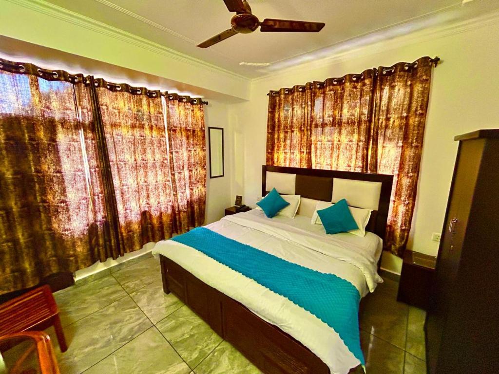 Un dormitorio con una cama grande con almohadas azules. en Hotel Om Palace Mcleodganj HP, en Dharamshala