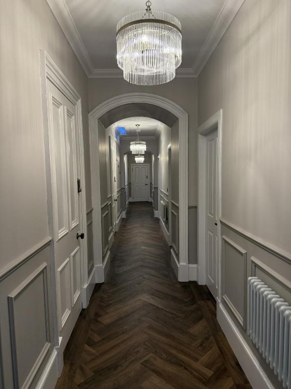 an empty hallway with a chandelier in a building at Murraygate Townhouse in Dundee