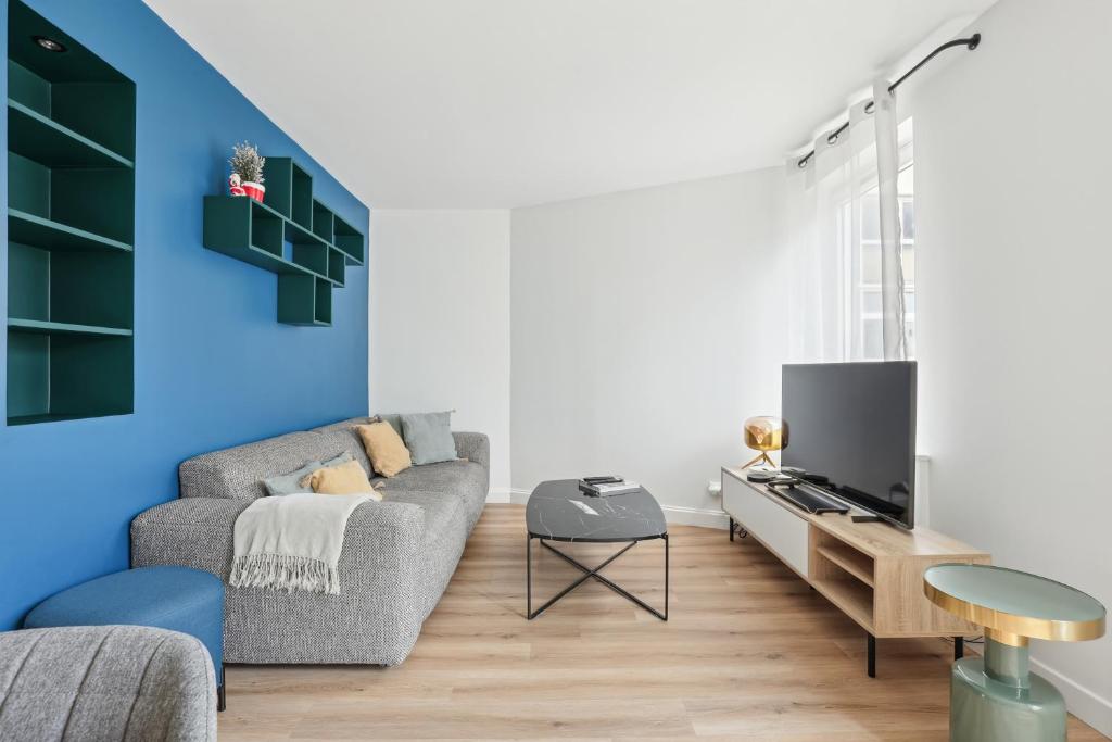 un salon avec un canapé et une télévision dans l'établissement Appartement elegant- Parc Saint Cloud, à Sèvres