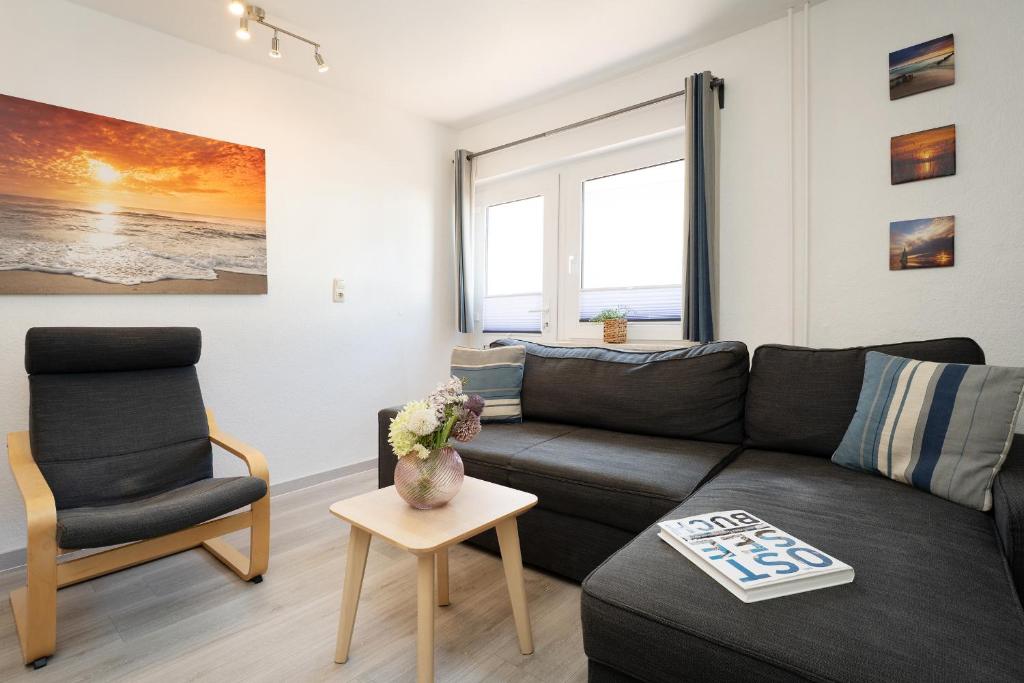 a living room with a black couch and a chair at Gästehaus Sulsdorf Wohnung 20 in Sulsdorf auf Fehmarn
