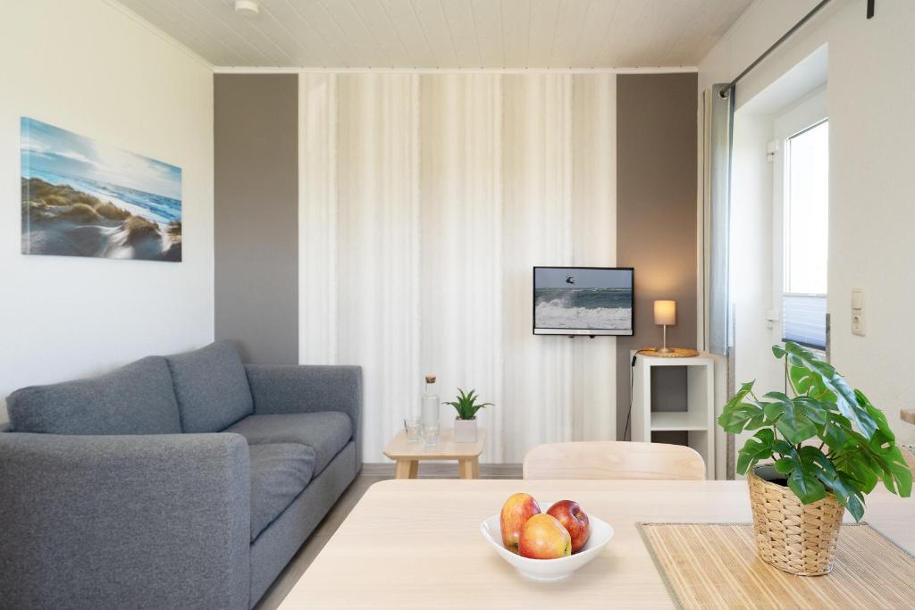 a living room with a couch and a bowl of fruit on a table at Gästehaus Sulsdorf Wohnung 1 in Sulsdorf auf Fehmarn