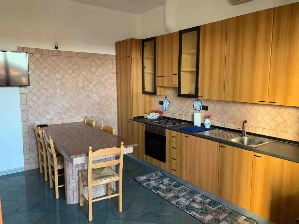a kitchen with wooden cabinets and a table with chairs at The Blue House in Roccella Ionica