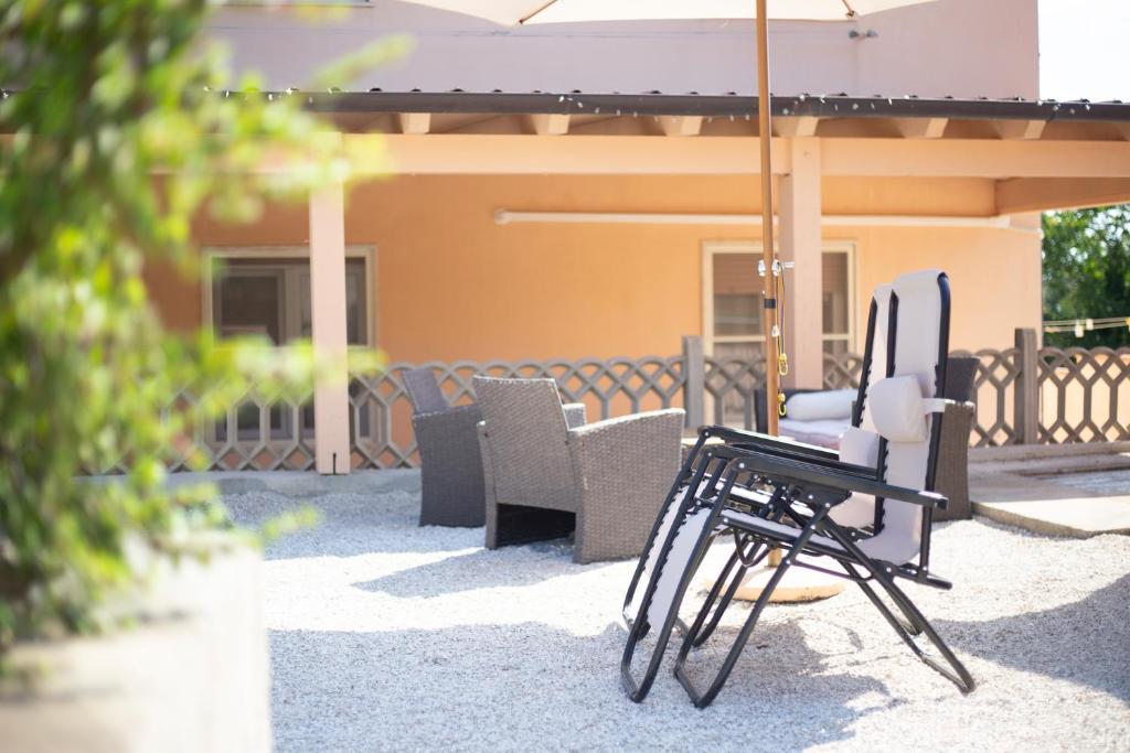un groupe de chaises et un parasol sur une terrasse dans l'établissement Il Giardino di Rio - HelloElba, à Rio Marina