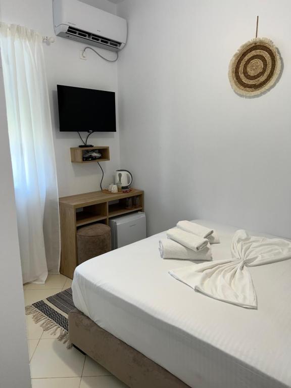 ein weißes Schlafzimmer mit einem Bett und einem Fernseher in der Unterkunft Helios Rooms in Sarandë