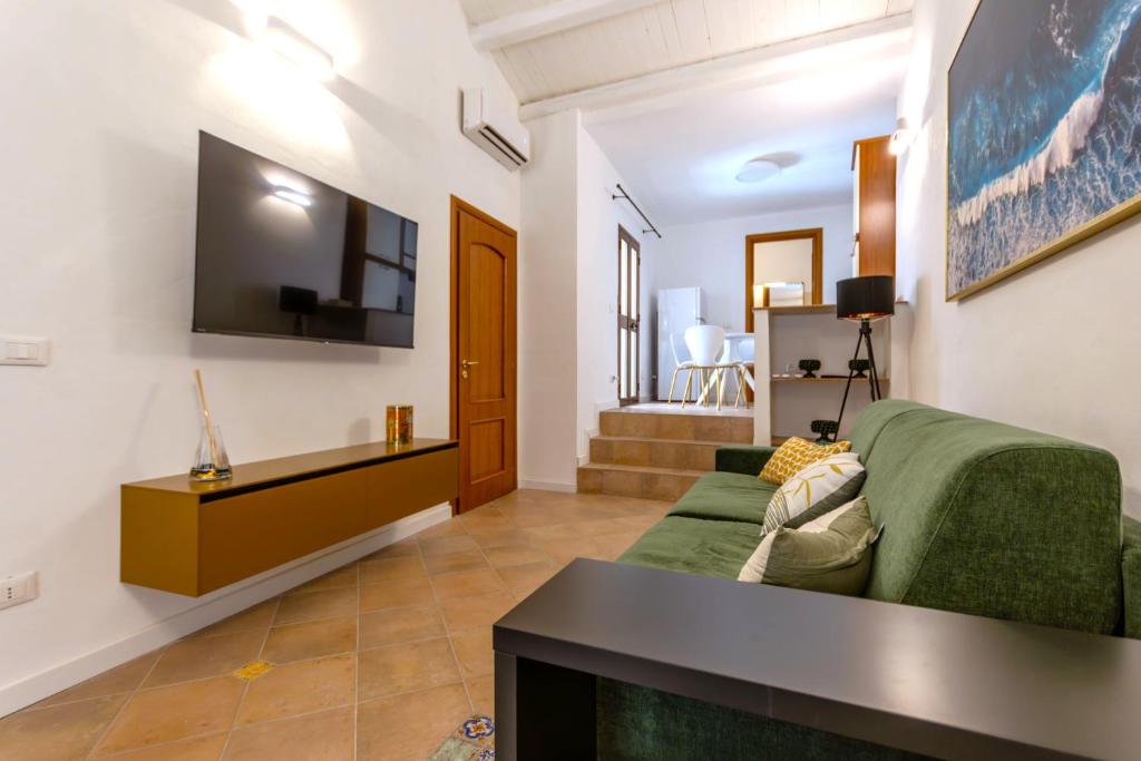 a living room with a green couch and a flat screen tv at Casa Vico Ferruccio 24 in Noto