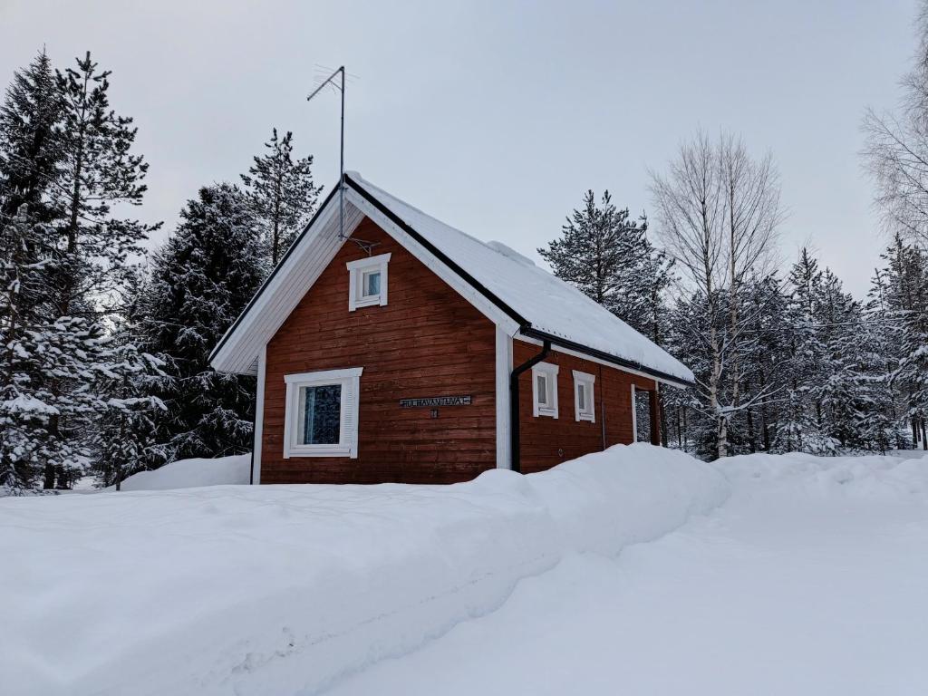 un pequeño edificio rojo en la nieve con árboles en Hulhavantuvat 1, en Syöte