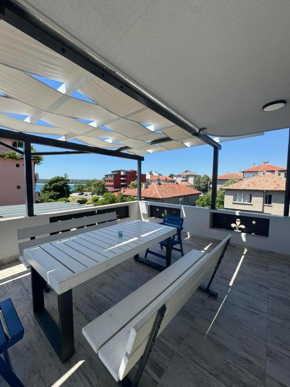 a patio with a table and benches on a roof at Апартаменти Лилия 2 in Primorsko