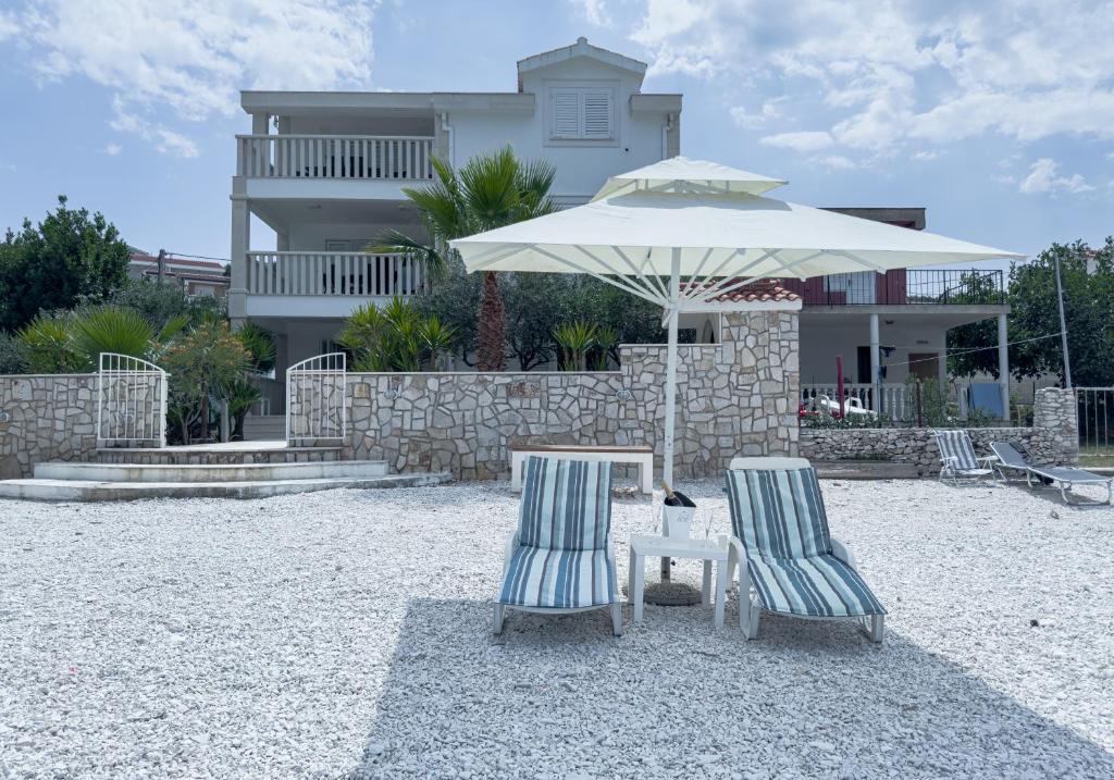 two chairs and an umbrella in front of a house at Luxury Beachfront Apartments Matista in Trogir