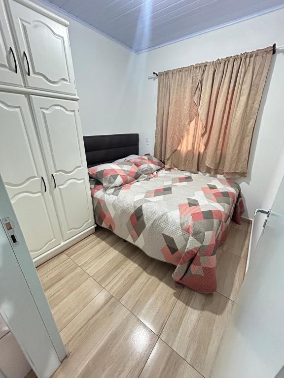 a small bedroom with a bed and a window at Micro casa Maju in Cascavel