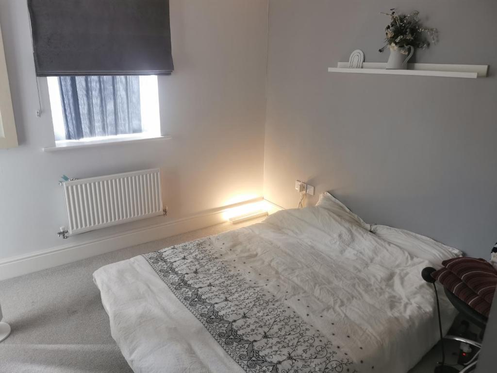 ein weißes Schlafzimmer mit einem Bett mit einer Lampe darauf in der Unterkunft The Grange Cute Modern Stay in Gerrards Cross