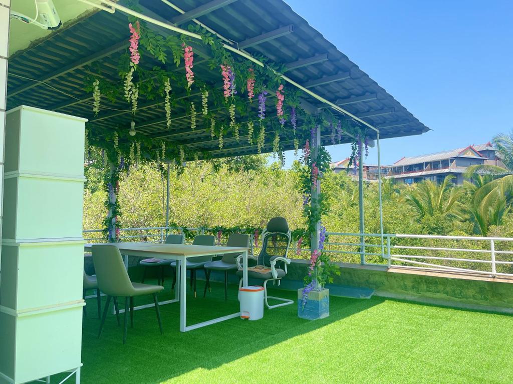 景洪にあるQingxinju Youth Hostelのパティオ(パーゴラの下にテーブルと椅子付)