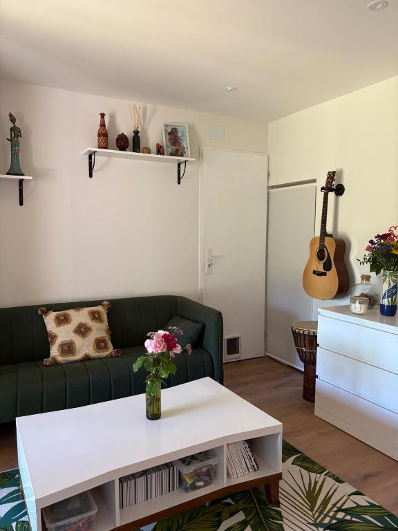 un soggiorno con un divano verde e un tavolo di Plein Sud -Maison proche centre, idéal famille a Montauban