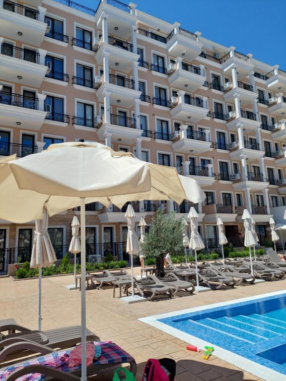 a hotel with chairs and an umbrella and a swimming pool at Sunshine Rose - Sea view, Neubau, Luxus Apartment in Sveti Vlas