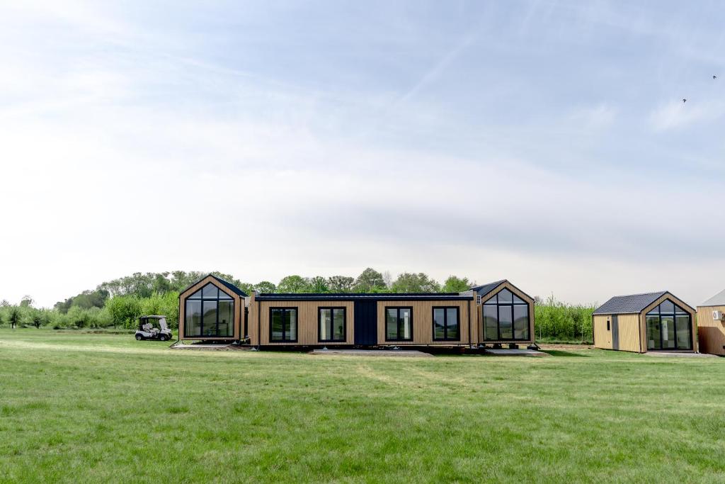 una casa con ventanas de cristal y un campo verde en Black Water Links Village, 