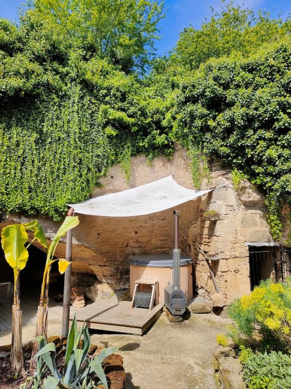 a patio with a white umbrella and a grill at Evasion Troglodyte insolite spa et nature in Doué-la-Fontaine
