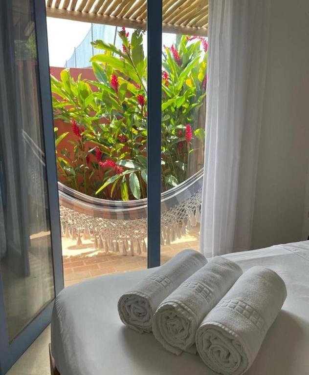 three rolled towels on a bed in front of a window at Villa Tennis in Ubatuba